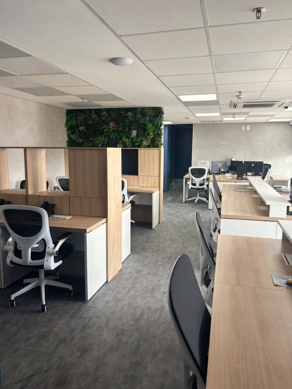 Ambiente de escritório moderno com mesas, cadeiras e sistema de automação para controle de ambiente e exaustão.