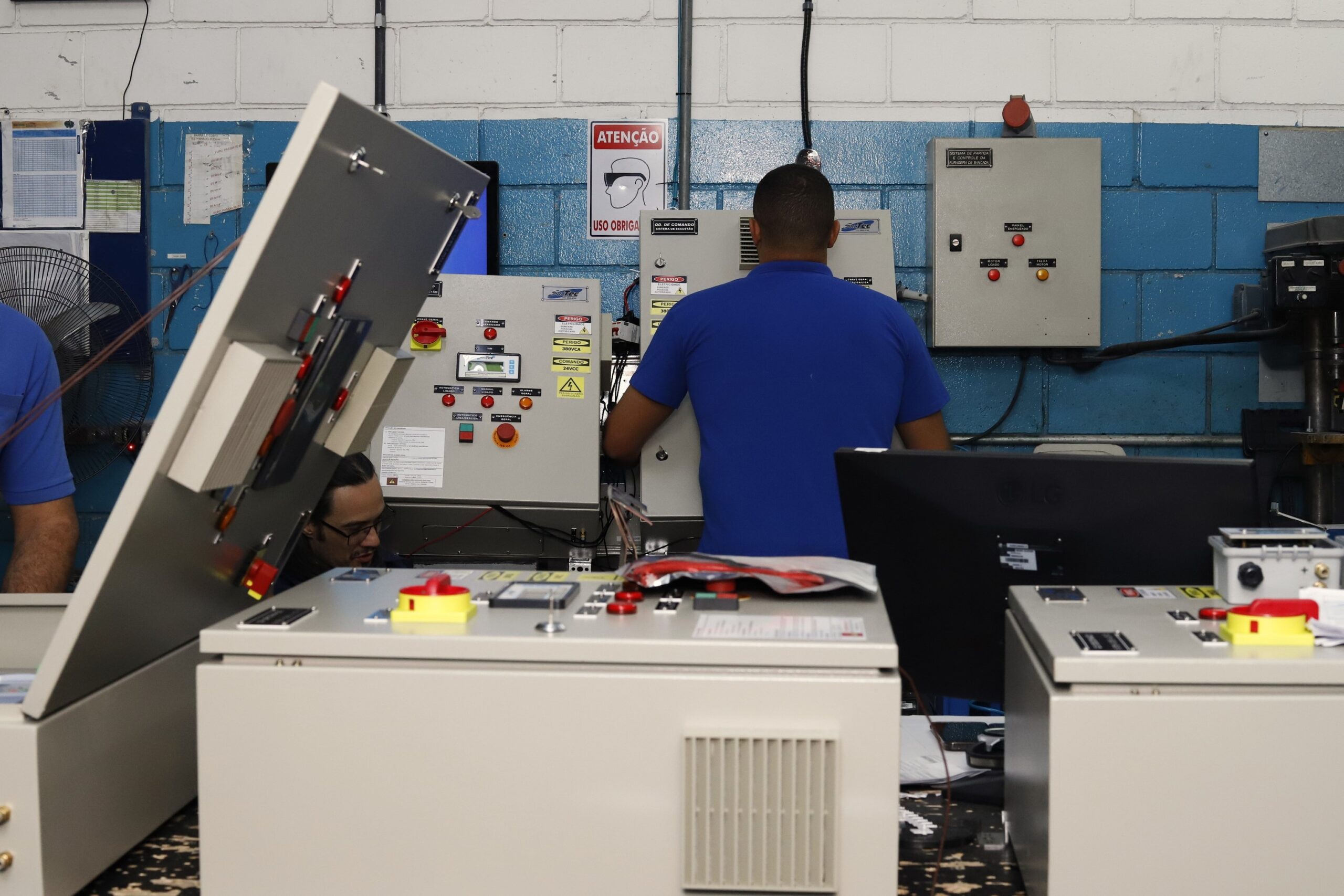Painel de controle de automação industrial com operadores, equipamentos de controle e sistemas de exaustão.