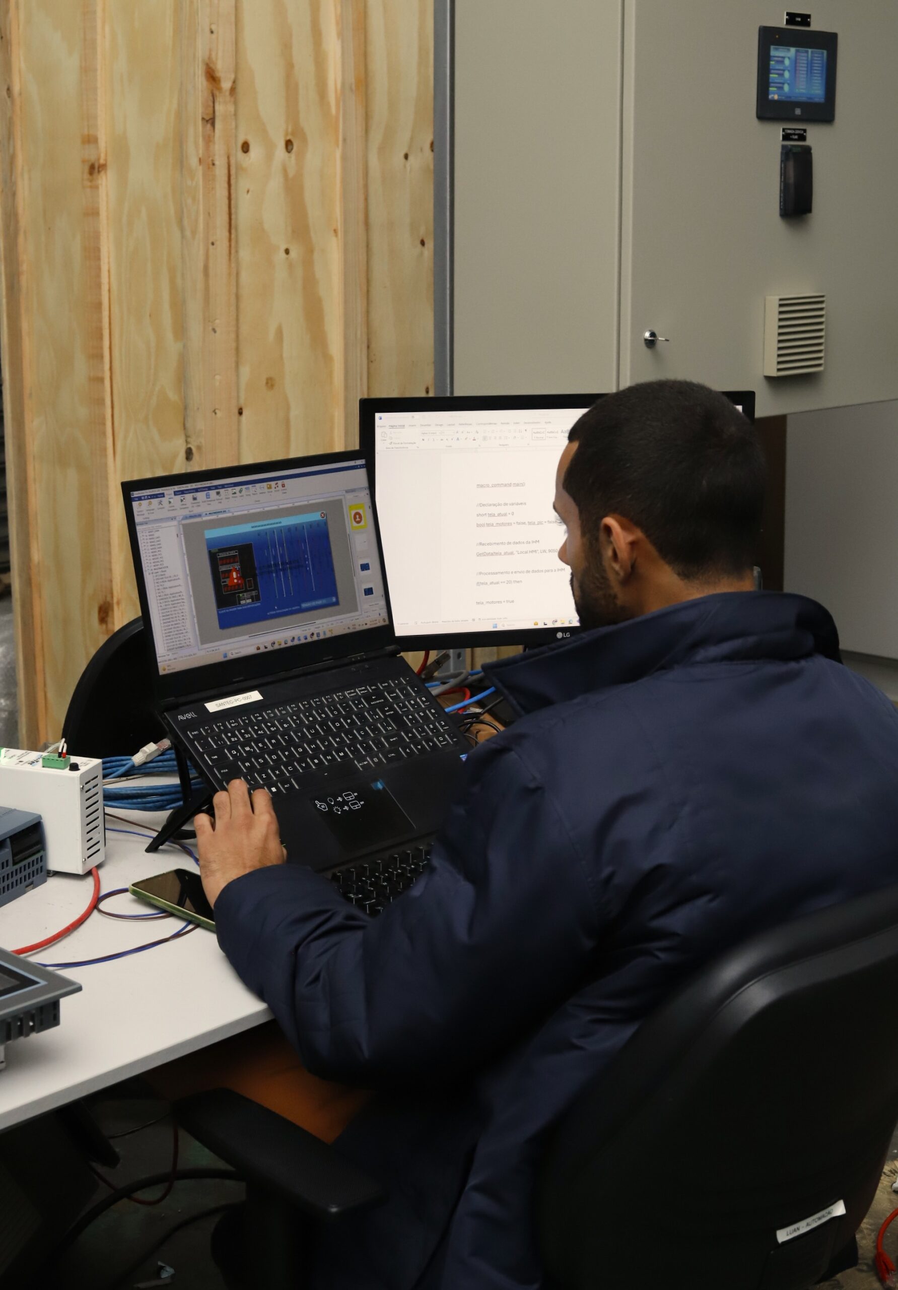 Técnico em automação industrial operando sistema BMS em computadores, monitorando controle de equipamentos e sensores.