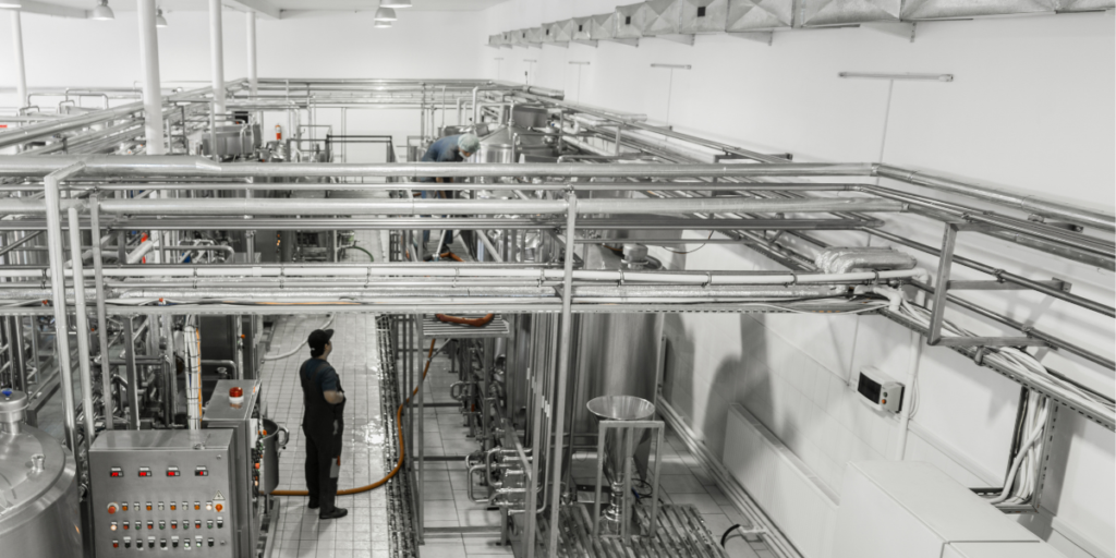 Instalação industrial com tubulações, equipamentos de controle e operadores, destacando automação e eficiência no p...