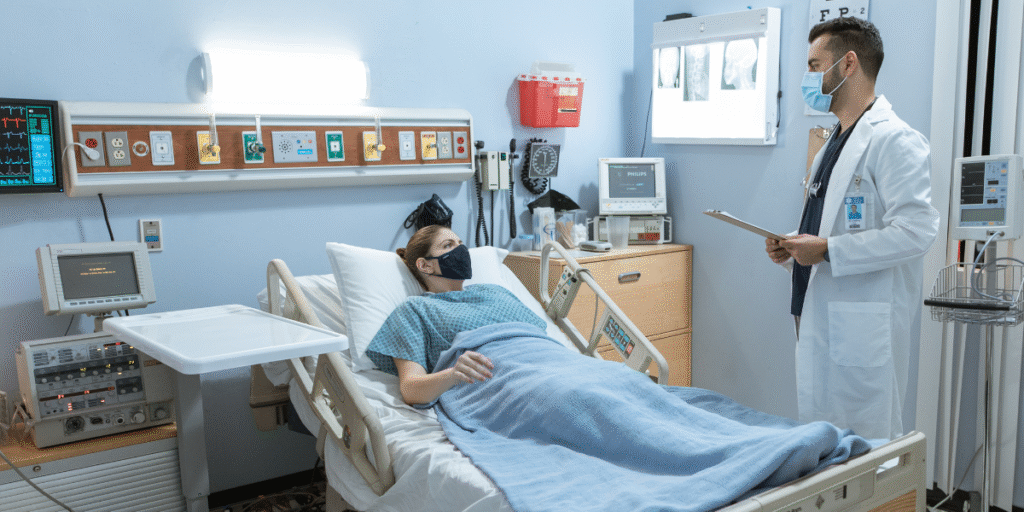 Médico em leito hospitalar monitora paciente, destacando a importância da automação em ambientes de saúde.